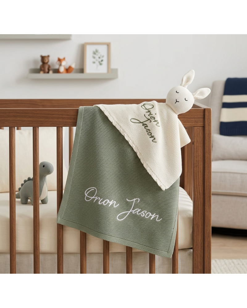 Baby crib with personalized green blanket and white bunny toy in a nursery setting.