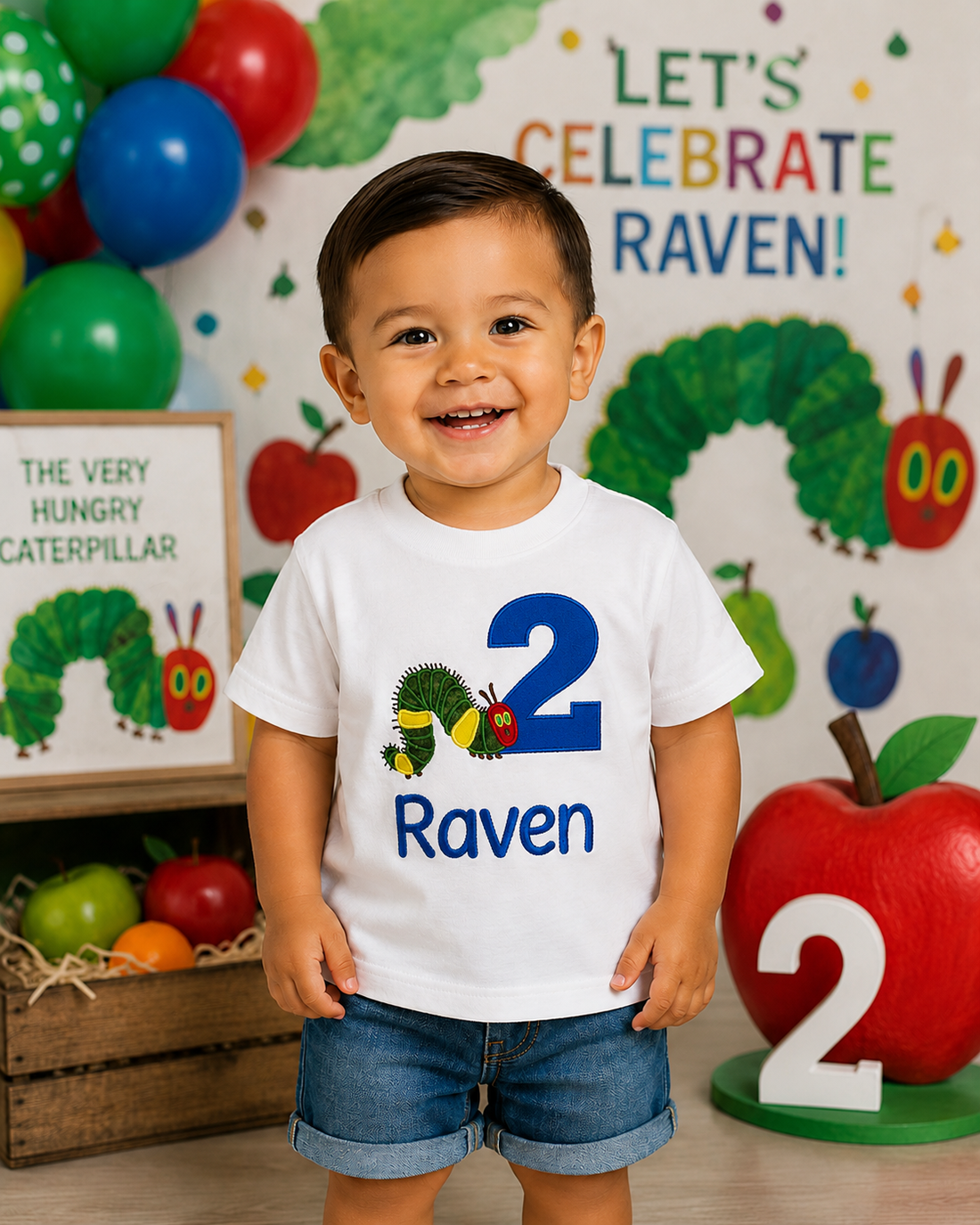 Personalized embroidered caterpillar 2nd birthday shirt for boys featuring a blue number 2, adorable caterpillar, and custom embroidered name Raven on a white 100% cotton shirt displayed at a caterpillar-themed second birthday party. | RoJo Custom Designs