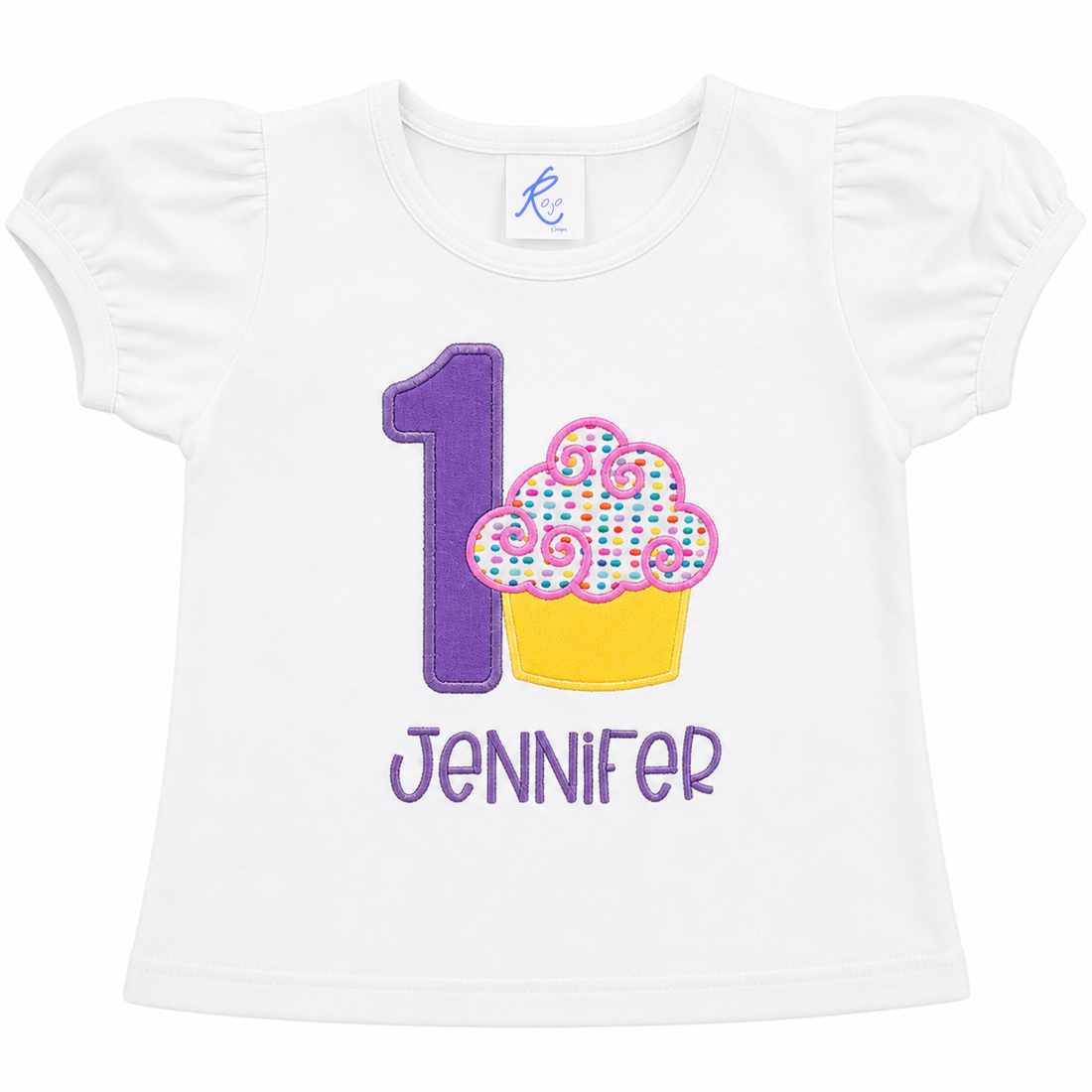 Personalized embroidered first birthday cupcake shirt for girls featuring a purple number 1, colorful sprinkled cupcake, and custom embroidered name Jennifer on a white 100% cotton birthday shirt by RoJo Custom Designs.