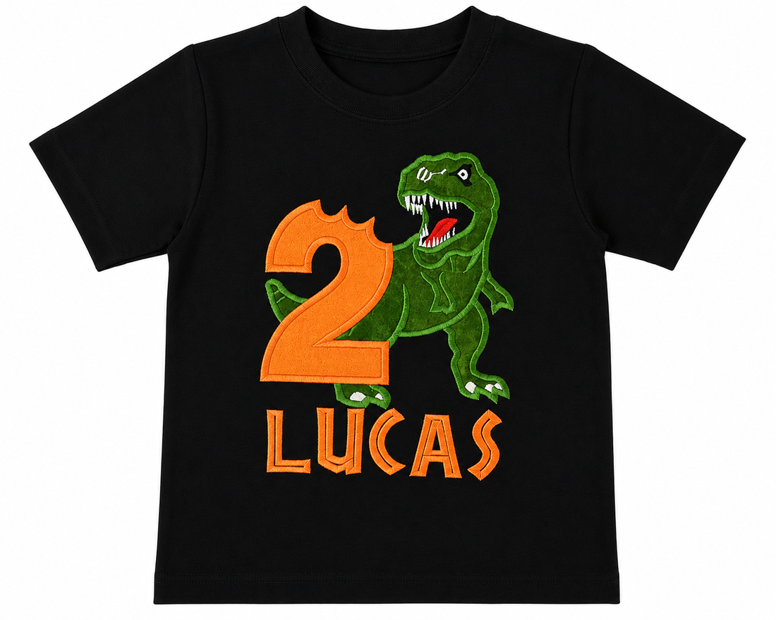 Personalized embroidered dinosaur birthday shirt for boys featuring a green T-Rex, orange number 2, and custom embroidered name Lucas on a black 100% cotton shirt at a dinosaur-themed birthday party. | RoJo Custom Designs